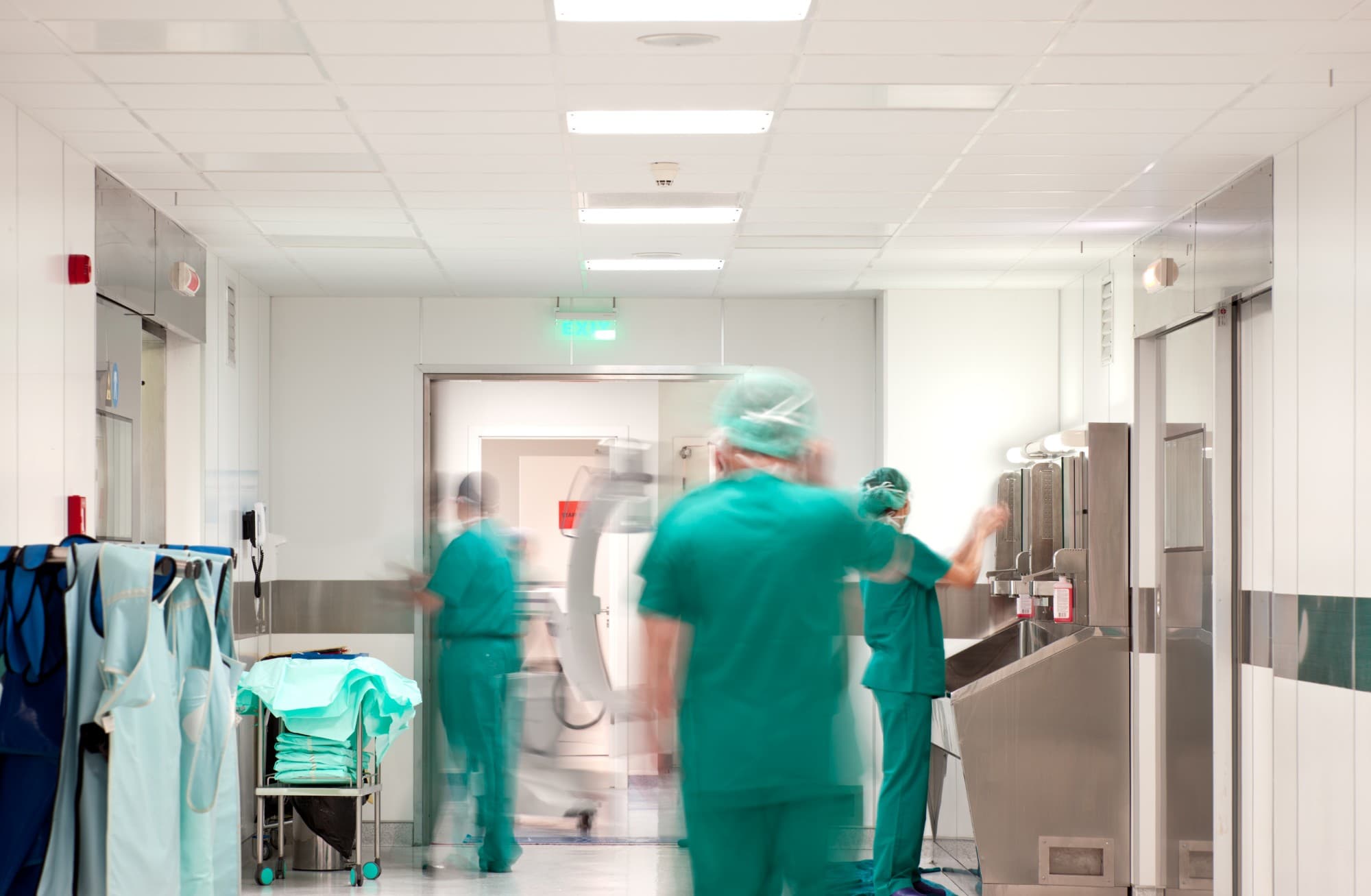 Staff in scrubs at work in a busy hospital corridor outside the operating rooms