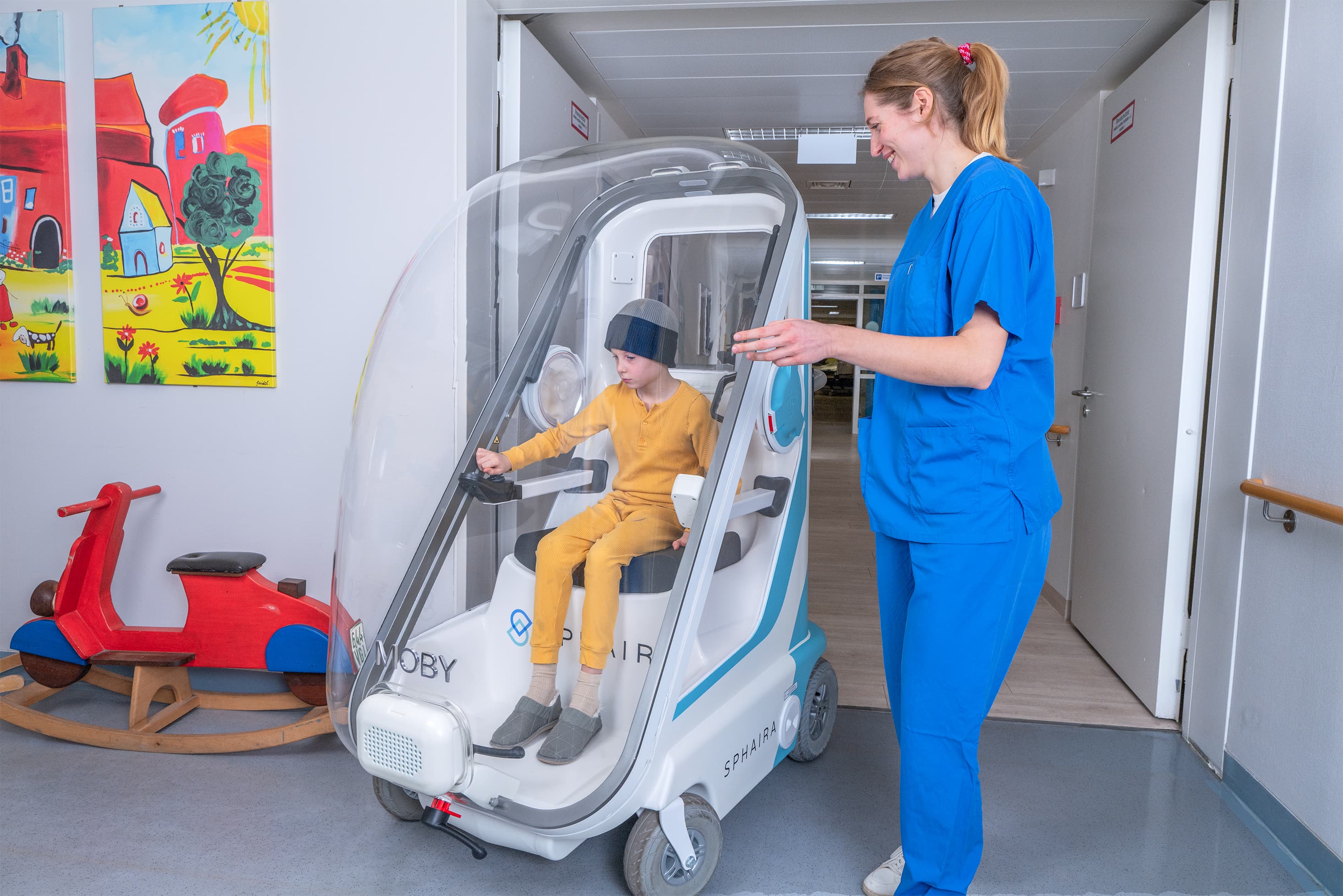 A nurse walks beside a boy in MOBY on a ward corridor